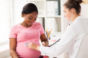 A doctor taking a pregnant patient's heart rate to represent the myth correlating heart rate and gender