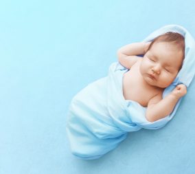 sleeping baby boy wrapped up in a blue blanket