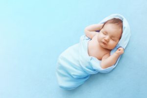 sleeping baby boy wrapped up in a blue blanket