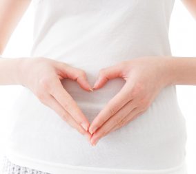 A woman making the shape of a heart with her hands over her belly to represent VBAC