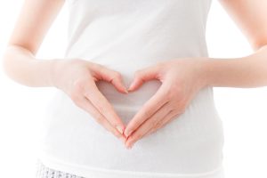 A woman making the shape of a heart with her hands over her belly to represent VBAC