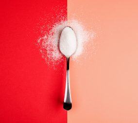 sugar with spoon on red and yellow background to represent the effects of artificial sweeteners in pregnancy