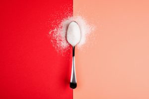 sugar with spoon on red and yellow background to represent the effects of artificial sweeteners in pregnancy
