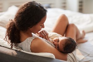 High angle portrait of young African-American mother breastfeeding cute baby boy with child looking at camera