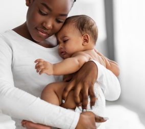 Mother holding crying baby to represent the importance or protecting your child from pertussis