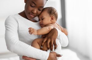 Mother holding crying baby to represent the importance or protecting your child from pertussis