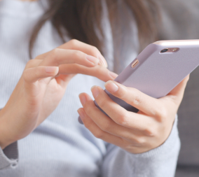 A woman in her first trimester dialing a number on her cell phone