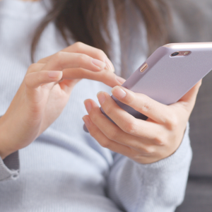 A woman in her first trimester dialing a number on her cell phone