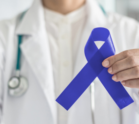 A doctor holding up a blue awareness ribbon in honor of colon cancer awareness month