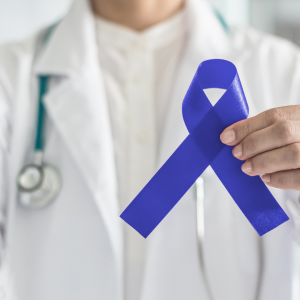 A doctor holding up a blue awareness ribbon in honor of colon cancer awareness month