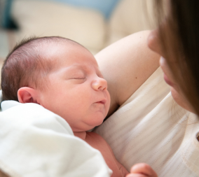 a woman holding a newborn to represent the relationship between heartburn and hair growth