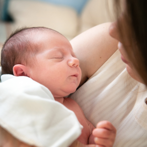 a woman holding a newborn to represent the relationship between heartburn and hair growth
