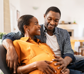 A young couple sitting together. The woman is pregnant and the couple is discussing birth plans.