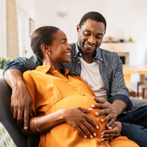 A young couple sitting together. The woman is pregnant and the couple is discussing birth plans.