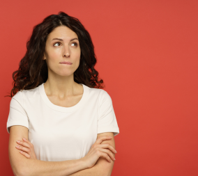 A woman in front of a red background wondering about her vaginal discharge