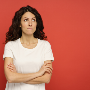 A woman in front of a red background wondering about her vaginal discharge