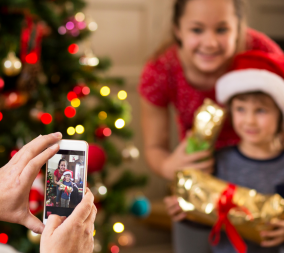 An iphone taking a photo of two kids in front of a christmas tree to represent photographing your children