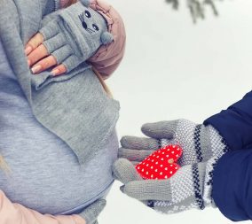 A pregnant woman in the winter snow to represent winter skincare in pregnancy