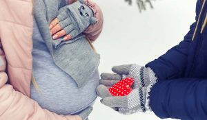 A pregnant woman in the winter snow to represent winter skincare in pregnancy
