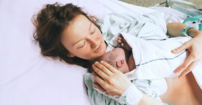 Mother holding her newborn baby child after induction of labor in a hospital.