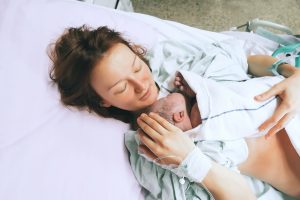 Mother holding her newborn baby child after induction of labor in a hospital.